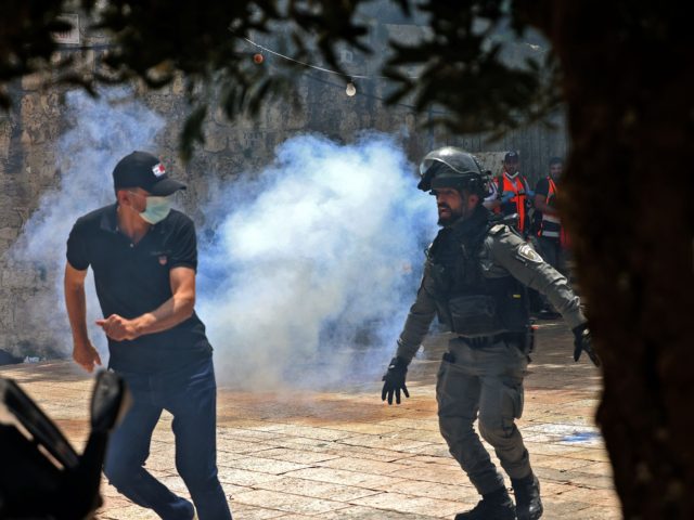 Palestinians run for cover from tear gas fired by Israeli security forces in Jerusalem's Old City on May 10, 2021, ahead of a planned march to commemorate Israel's takeover of Jerusalem in the 1967 Six-Day War. (Photo by EMMANUEL DUNAND / AFP) (Photo by EMMANUEL DUNAND/AFP via Getty Images)