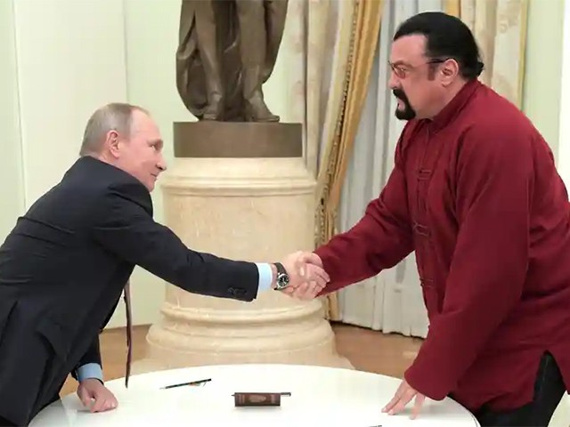 Vladimir Putin (left) shakes hands with Steven Seagal after presenting him with a Russian passport during a meeting at the Kremlin in Moscow, on November 25, 2016