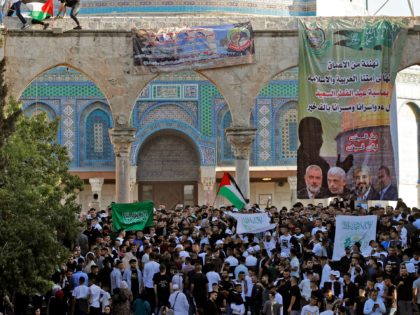 Palestinian worshippers raise the Hamas and the Palestinian flag along with a Hamas poster with portraits of its leaders, at the Dome of the Rock shrine in the al-Aqsa mosques compound in Jerusalem's Old City, on May 13, 2021, after Eid al-Fitr prayers, which marks the end of the holy …
