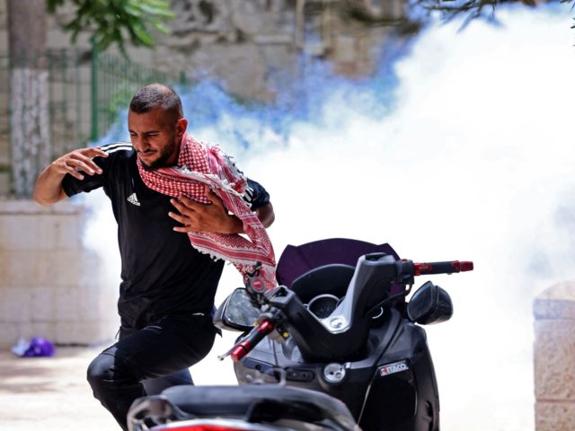 A Palestinian protester runs for cover from tear gas fired by Israeli security forces in Jerusalem's Old City on May 10, 2021, as a planned march marking Israel's 1967 takeover of the holy city threatened to further inflame tensions. (Photo by EMMANUEL DUNAND / AFP) (Photo by EMMANUEL DUNAND/AFP via …