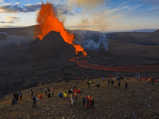 People watch as lava flows from an eruption from the Fagradalsfjall volcano on the Reykjan