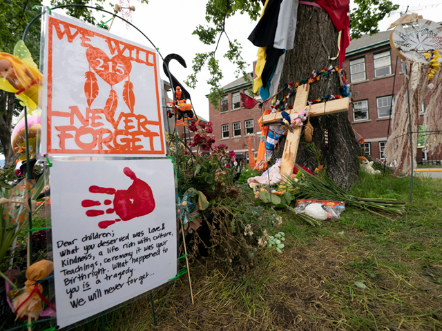 Signs are pictured at a memorial outside the Residential School in Kamloops, British Columbia., Sunday, June, 13, 2021. The remains of 215 children were discovered buried near the former Kamloops Indian Residential School earlier this month. (Jonathan Hayward/The Canadian Press via AP)