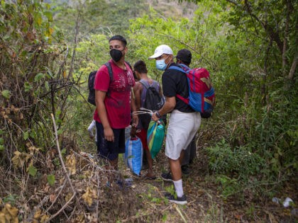 Honduran migrants observe a police checkpoint as they take an alternative route to avoid being detained in Chiquimula, Guatemala, Tuesday, Jan. 19, 2021. While Guatemala focused on the the year's first caravan other migrants moved north as always in small, discreet groups. It was during the caravan last month that …