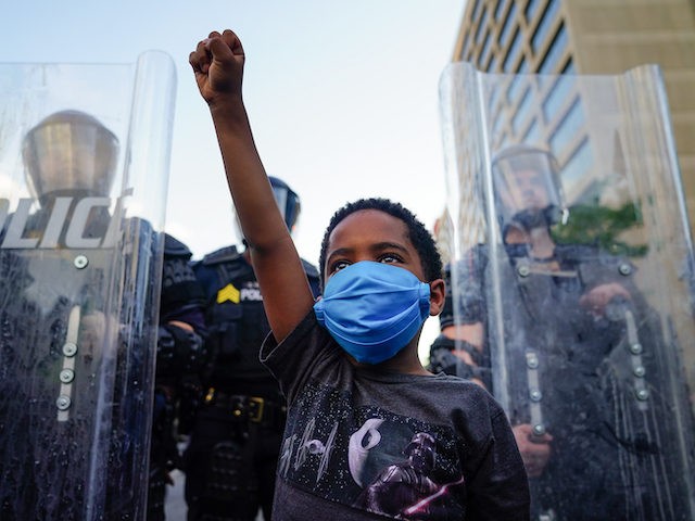 ATLANTA, GA - MAY 31: A young boy raises his fist for a photo by a family friend during a demonstration over the Minneapolis death of George Floyd while in police custody on May 31, 2020 in Atlanta, Georgia. (Photo by Elijah Nouvelage/Getty Images)