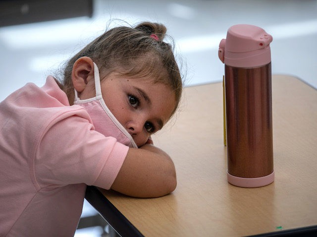 STAMFORD, CONNECTICUT - SEPTEMBER 09: Harper Shea (5), lays her head down on her desk near the end of her first day of kindergarten on September 9, 2020 in Stamford, Connecticut. For millions of kindergartners attending in-school classes for the first time, wearing masks and social distancing at school isn't …