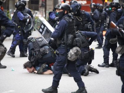 Police special tactical squad detain a protester (C) in Wanchai, Hong Kong on May 24, 2020, as thousands of demonstrators took to the streets to protest against a national security law. - The proposed legislation is expected to ban treason, subversion and sedition, and follows repeated warnings from Beijing that …