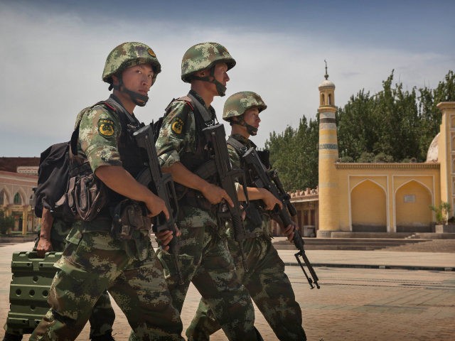 KASHGAR, CHINA - JULY 31: Chinese soldiers march in front of the Id Kah Mosque, China's largest, on July 31, 2014 in Kashgar, China. China has increased security in many parts of the restive Xinjiang Uyghur Autonomous Region following some of the worst violence in months in the Uyghur dominated …