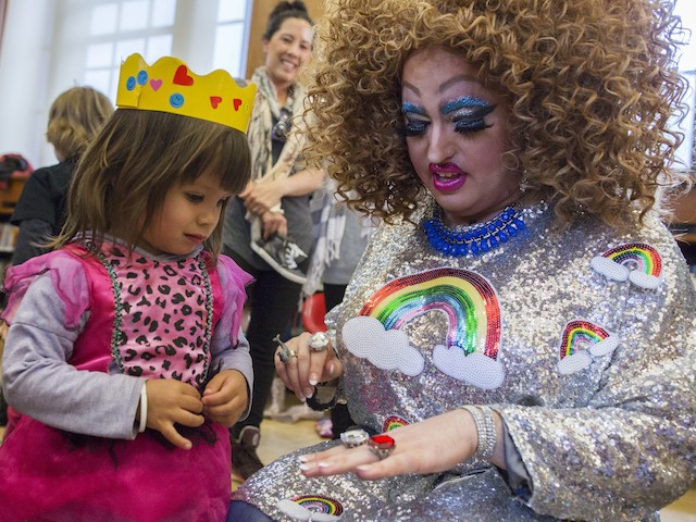 In this Saturday, May 13, 2017 photo, Lil Miss Hot Mess, right, compares outfits with 2-year old Eva McInnes after reading to a group of children during the Feminist Press' presentation of Drag Queen Story Hour! at the Park Slope Branch of the Brooklyn Public Library, in New York. (AP Photo/Mary Altaffer)