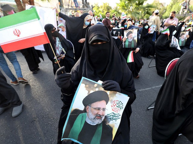 Supporters of Iranian ultraconservative presidential candidate Ebrahim Raisi carry posters bearing his portrait and wave national flags as they attend a rally in the capital Tehran, on June 16, 2021, ahead of the Islamic republic's June 18 presidential election. - The field of candidates in Iran's presidential election thinned today, …
