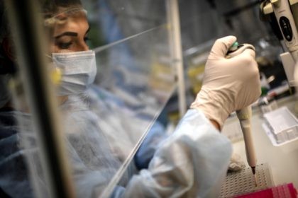 A laboratory technician wearing protective equipment works on the genome sequencing of the SARS-CoV-2 virus (Covid-19) and its variants at the Centre National de Reference (CNR - National Reference Centre) of respiratory infections viruses of the Pasteur Institute in Paris on January 21, 2021. (Photo by Christophe ARCHAMBAULT / AFP) …