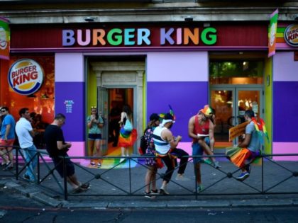 Members of the Lesbian, Gay, Bisexual, Transgender, Intersex and Queer (LGBTIQ) community wait outside a Burger King restaurant decorated with the colors of the rainbow flag before the annual Pride parade in Madrid, on July 6, 2019. (Photo by OSCAR DEL POZO / AFP) (Photo credit should read OSCAR DEL …