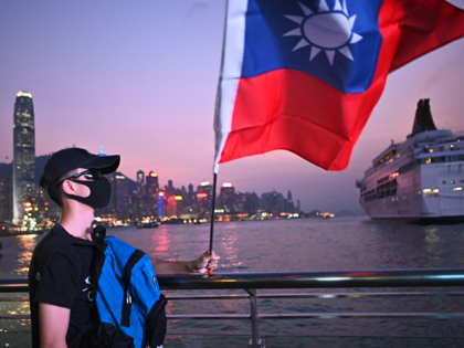 A man wearing a mask holds a Taiwanese flag as he joins others at a rally to mark Taiwan's