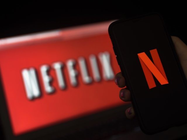 In this photo illustration a computer screen and mobile phone display the Netflix logo on