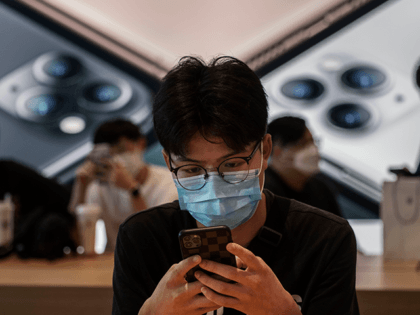 A Chinese customer looks at a phone at the official opening of the new Apple Store in the Sanlitun shopping area on July 17, 2020 in Beijing, China. The new store replaces Apple's first ever China store which opened in 2008 prior to the Beijing Olympics adjacent to the new …