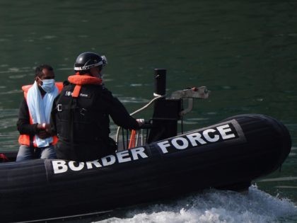 UK Border Force officials escort migrants intercepted whilst travelling in a RIB from France to Dover ashore at the Marina in Dover, southeast England on August 13, 2020. - British Prime Minister Boris Johnson on Monday said illegal migrant crossings of the Channel, which have hit record numbers, were "very …