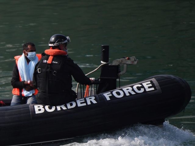UK Border Force officials escort migrants intercepted whilst travelling in a RIB from Fran