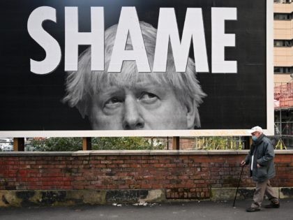 A man wearing a protective face mask passes a billboard showing Britain's Prime Minister B