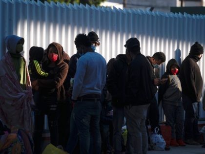 Asylum seekers wait outside El Chaparral crossing port as they try to cross to the United