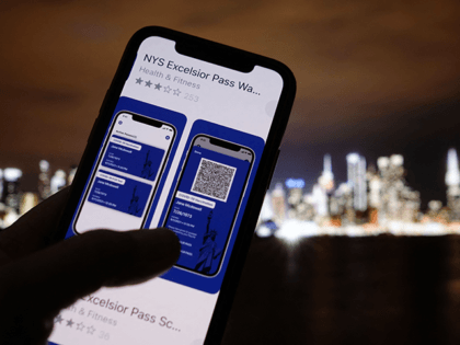 This illustration photo taken in Los Angeles on April 6, 2021 shows a person looking at the app for the New York State Excelsior Pass, which provides secure, digital proof of a Covid-19 vaccination, in front of a screen showing the New York skyline. - As the United States' vaccination …