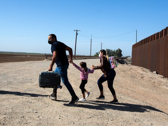 A family of migrants from Cuba runs across the border by the wall separating the United States and Mexico to turn themselves over to authorities on May 13, 2021 in Yuma, Arizona. - Apprehensions of undocumented immigrants at the US border with Mexico rose to a fresh 15-year high in …