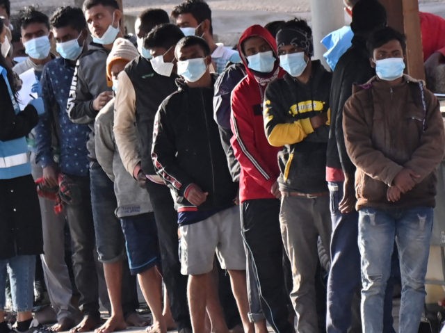 Migrants line up after disembarking on the southern Italian Pelagie Island of Lampedusa on May 17, 2021. - More than 1,400 migrants arrived on the Italian island of Lampedusa at the weekend, sparking calls from far-right politicians for action to stem the flow, amid fresh moves by Italian authorities against …