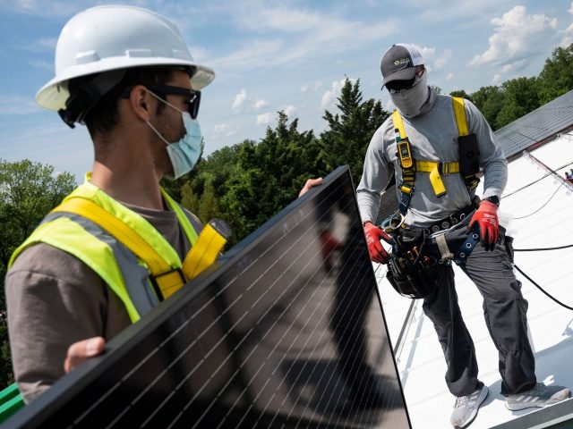 Employees with Ipsun Solar unload solar panels on the roof of the Peace Lutheran Church in Alexandria, Virginia on May 17, 2021. - Using donations, the church installed a 60.48 kilowatt solar instillation to bring down their carbon footprint. US President Joe Biden has called for the US energy sector …