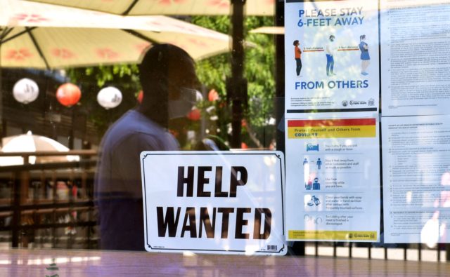 A 'Help Wanted' sign is posted beside Coronavirus safety guidelines in front of