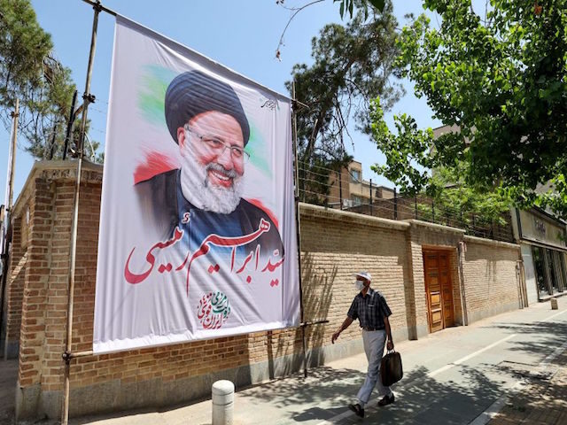 An Iranian man walks past an electoral poster depicting judiciary chief and presidential candidate Ebrahim Raisi in the capital Tehran, on May 29, 2021. - Iran's presidential election campaign officially kicked off yesterday, without fanfare and in an atmosphere of indifference as many say the result is a foregone conclusion. …