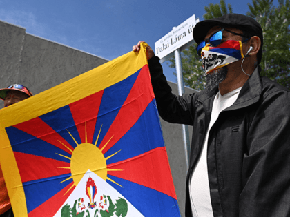 Activists hold the Tibetan flag underneath a street sign reading 'Dalai Lama street', close to a territory of the planned Chinese Fudan University campus, in 9th district, Ferencvaros of Budapest, Hungary on June 2, 2021. - Budapest has renamed streets around the planned site of a top Chinese university to …