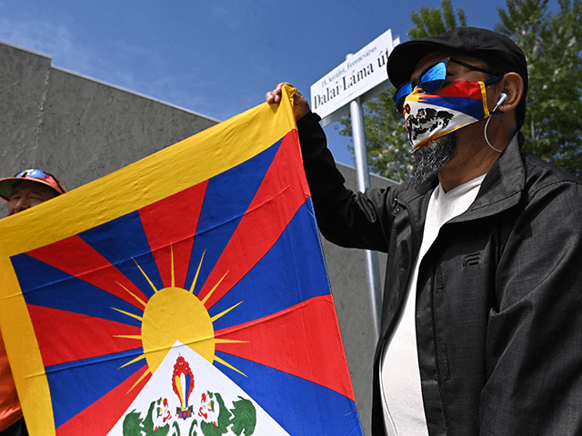 Activists hold the Tibetan flag underneath a street sign reading 'Dalai Lama street', clos