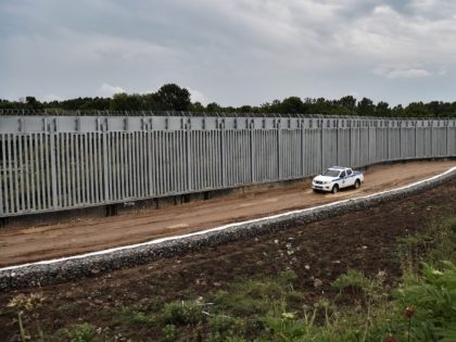 A police car patrols along a steel fence along Evros river, Greece's river border with Turkey, near the village of Poros on June 8, 2021. - The area is where the Greek State has chosen to deploy a new anti-migration arsenal including cameras, radar and a 40-kilometre (25-mile) steel fence …
