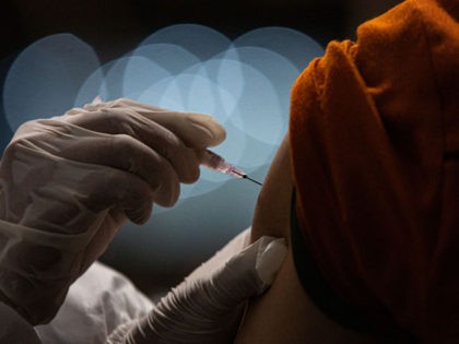 An Indonesian doctor injects a dose of Sinovac COVID-19 vaccine to a man during a COVID-19