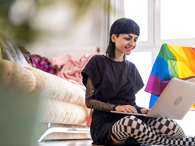 Happy non-binary person using laptop at home