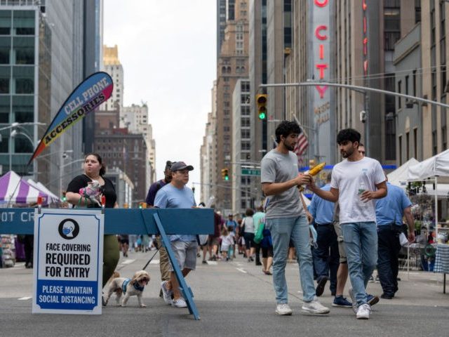 NEW YORK, NEW YORK - JUNE 20: People without masks walk near a COVID-19 protocols sign at