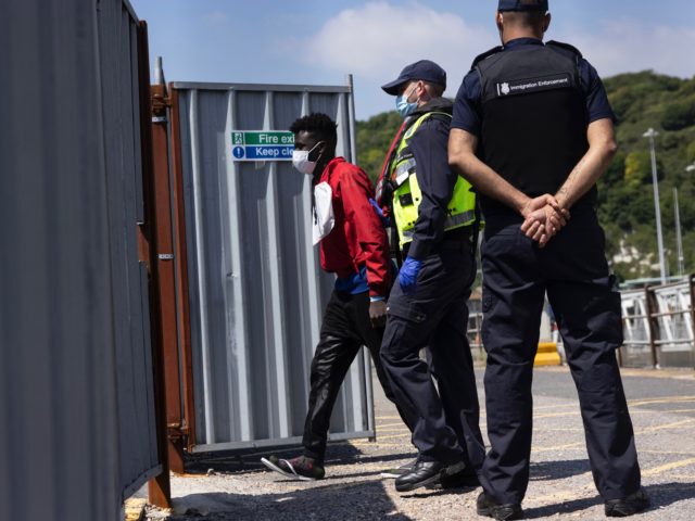 DOVER, ENGLAND - JUNE 24: Border Force officials guide newly arrived migrants to a holding