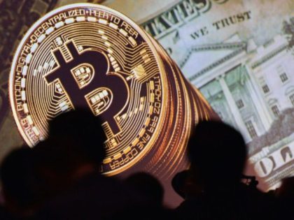 An image of Bitcoin and US currencies is displayed on a screen as delegates listen to a panel of speakers during the Interpol World Congress in Singapore on July 4, 2017. - The three-day conference on fostering innovation for future security challenges is taking place from July 4 to 6. …