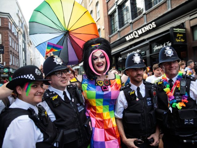 LONDON, ENGLAND - JULY 08: Police officers pose for a photograph with a reveller in Soho during the Pride in London Festival on July 8, 2017 in London, England. The Pride in London Festival sees hundreds of thousands of people take to the streets in celebration and support of the …