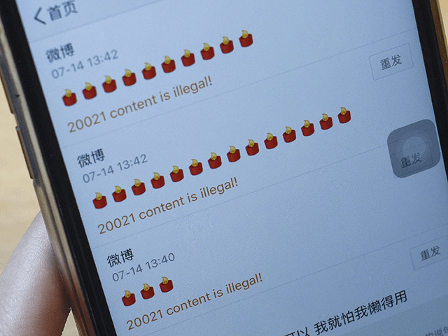 This photo illustration taken on July 14, 2017 shows a woman holding her phone in Beijing after trying to post a candle emoji in memory of late Chinese dissident Liu Xiaobo and getting a reply of "content is illegal". China's censors raced on July 14 to scrub social media networks …