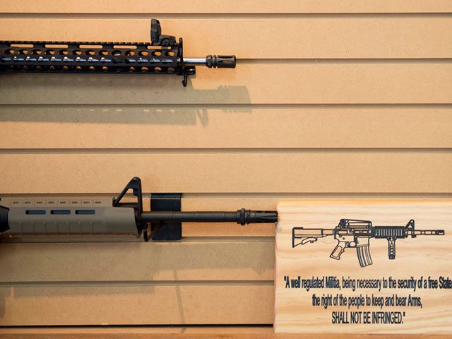 A placard about gun rights in the United States hangs on the wall next to assault rifles for sale at Blue Ridge Arsenal in Chantilly, Virginia, on October 6, 2017. (Photo by JIM WATSON / AFP) (Photo credit should read JIM WATSON/AFP via Getty Images)
