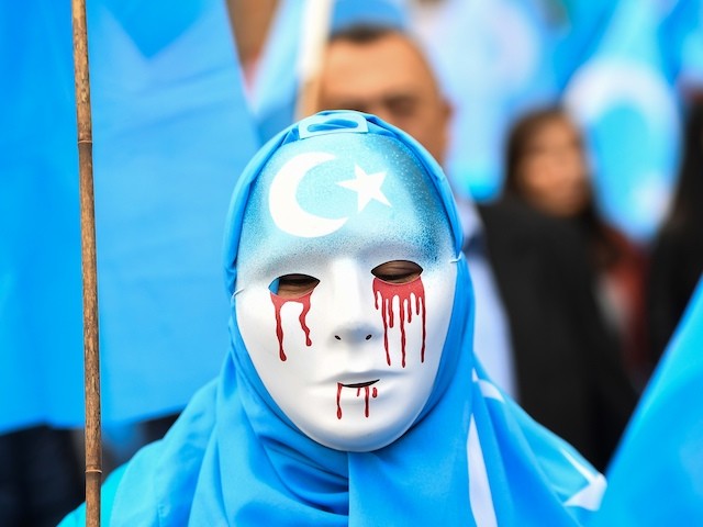 TOPSHOT - A person wearing a white mask with tears of blood takes part in a protest march of ethnic Uighurs asking for the European Union to call upon China to respect human rights in the Chinese Xinjiang region and ask for the closure of 