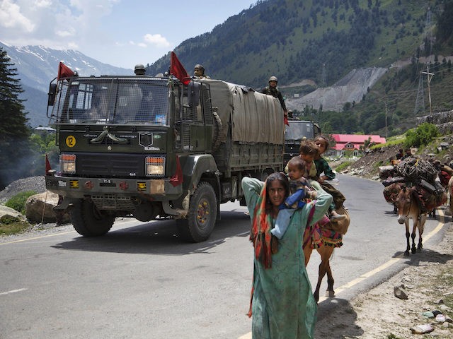 Kashmiri Bakarwal walks as Indian army soldier guard on top one the vehicle part of convoy
