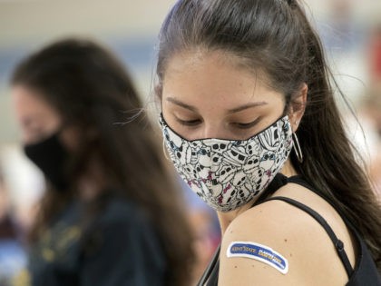 Kent State University student Regan Raeth of Hudson, Ohio, looks at her vaccination bandage as she waits for 15 minutes after her shot in Kent, Ohio, Thursday, April 8, 2021. (AP Photo/Phil Long)