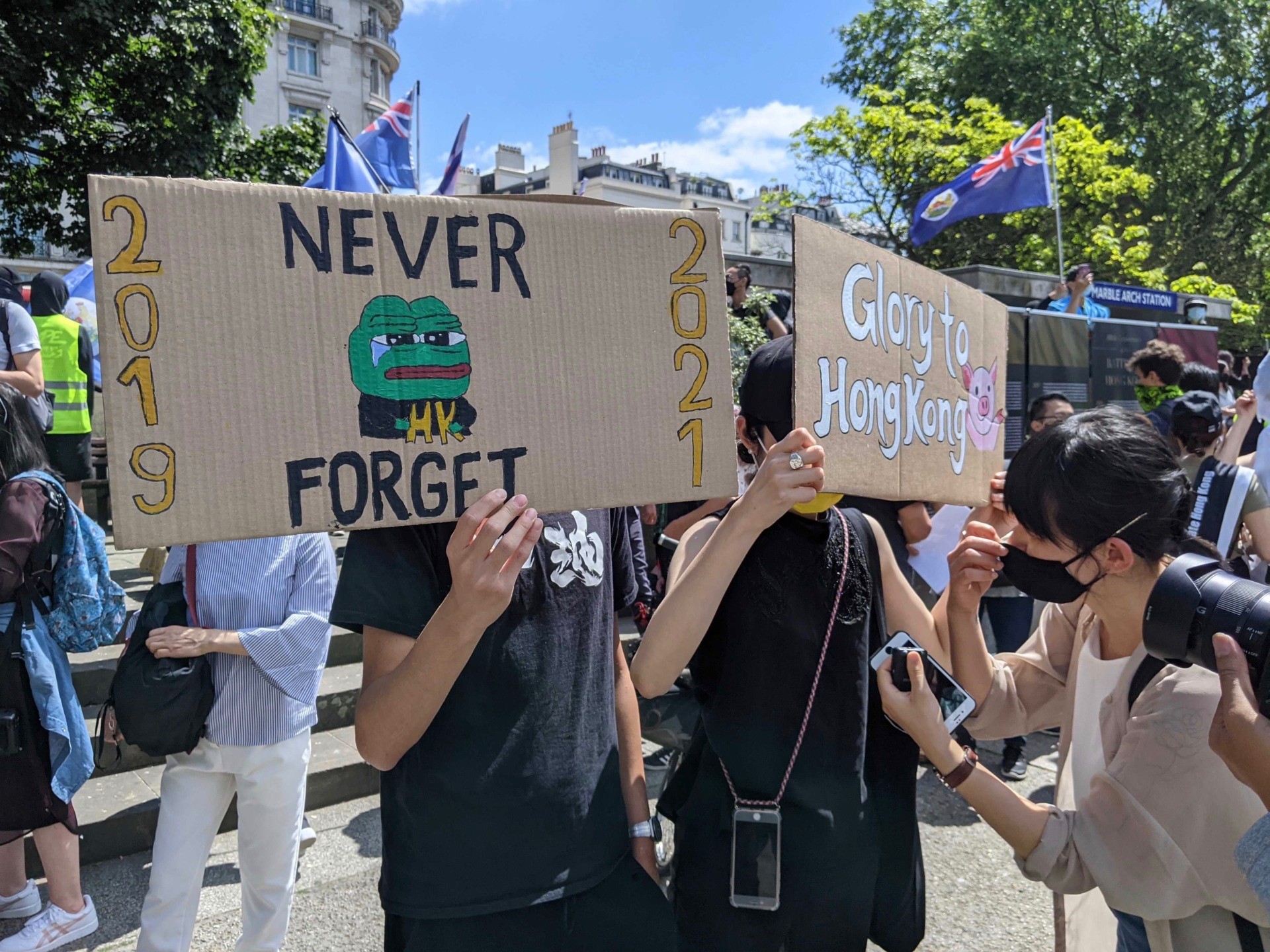 A protester holds a placard of Pepe the Frog (a symbol taken up by activists in Hong Kong) saying 'Never Forget'. June 12th, 2020. Kurt Zindulka, Breitbart News