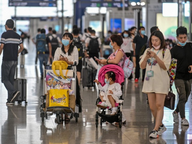 Passengers wearing facemasks walk across a hall following preventive procedures against th