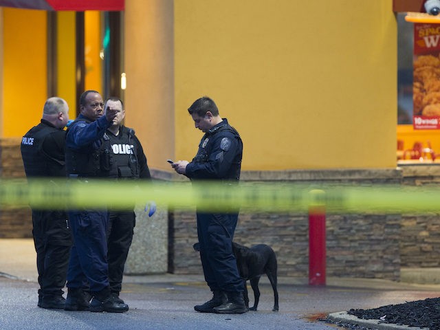 Police stand outside a Popeyes restaurant during an investigation into the shooting of a P