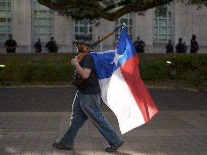 TOPSHOT - A man walks with a rifle with a Texas flag attached to it during a Police Appreciation rally at the City Hall in Houston, Texas on June 18, 2020. (Photo by Mark Felix / AFP) (Photo by MARK FELIX/AFP /AFP via Getty Images)