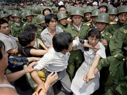 A young woman is caught between civilians and Chinese soldiers, who were trying to remove her from an assembly near the Great Hall of the People in Beijing, June 3, 1989. Pro-democracy protesters had been occupying Tiananmen Square for weeks. (AP Photo/Jeff Widener)