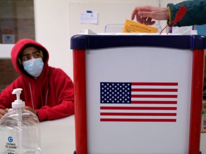Election inspector Taquaine Mason observes as a voter drops his ballot into the box during