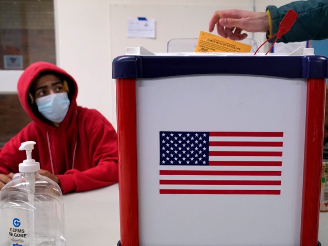 Election inspector Taquaine Mason observes as a voter drops his ballot into the box during early in-person voting, Thursday, Oct. 29, 2020, in Cambridge, Mass. (AP Photo/Elise Amendola)