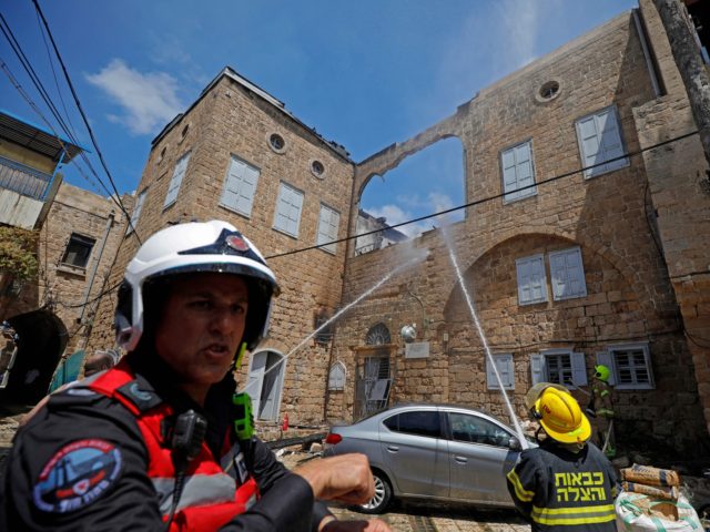 Firefighters extinguish fire from a building that was vandalised in Acre, a mixed Arab-Jewish town in northwest Israel, on May 13, 2021. - Israel faced an escalating conflict on two fronts, scrambling to quell riots between Arabs and Jews on its own streets after days of exchanging deadly fire with …